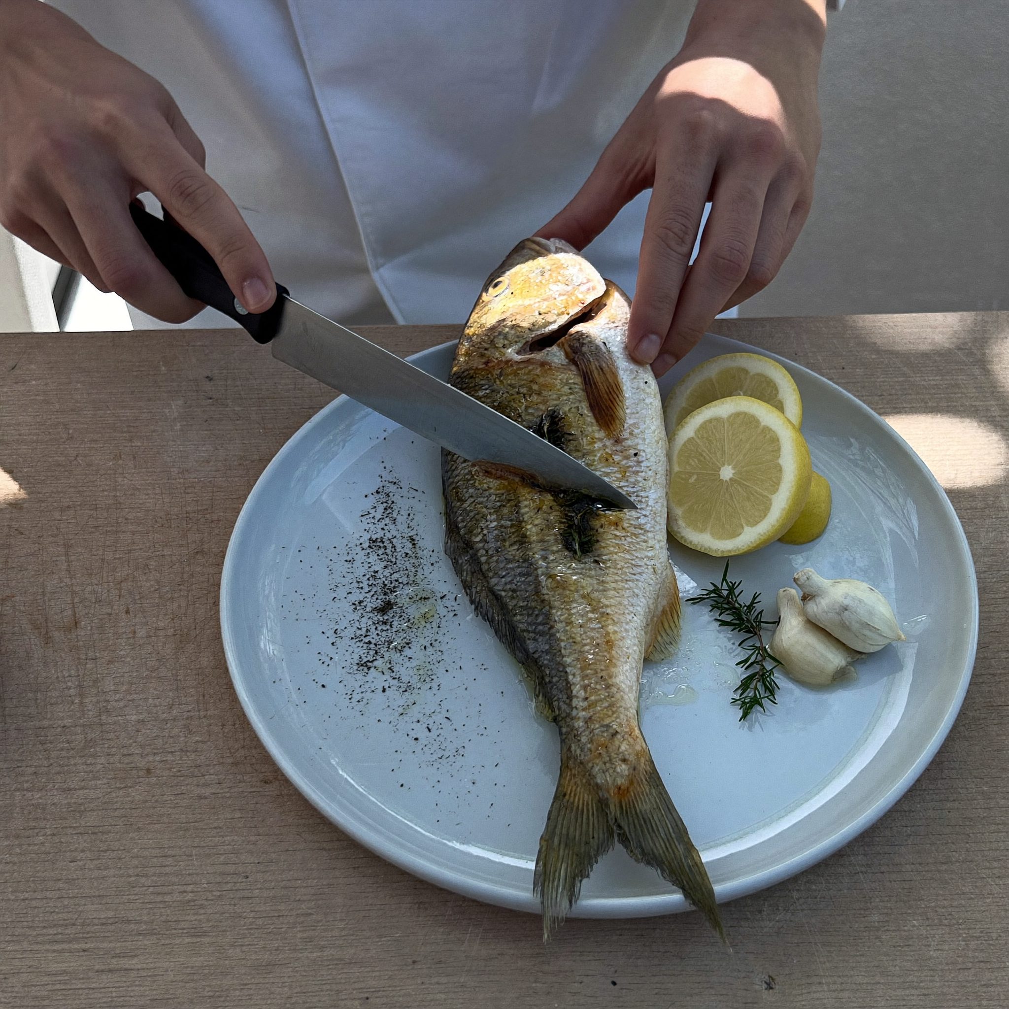 Mãos do chefe a empratar peixe fresco