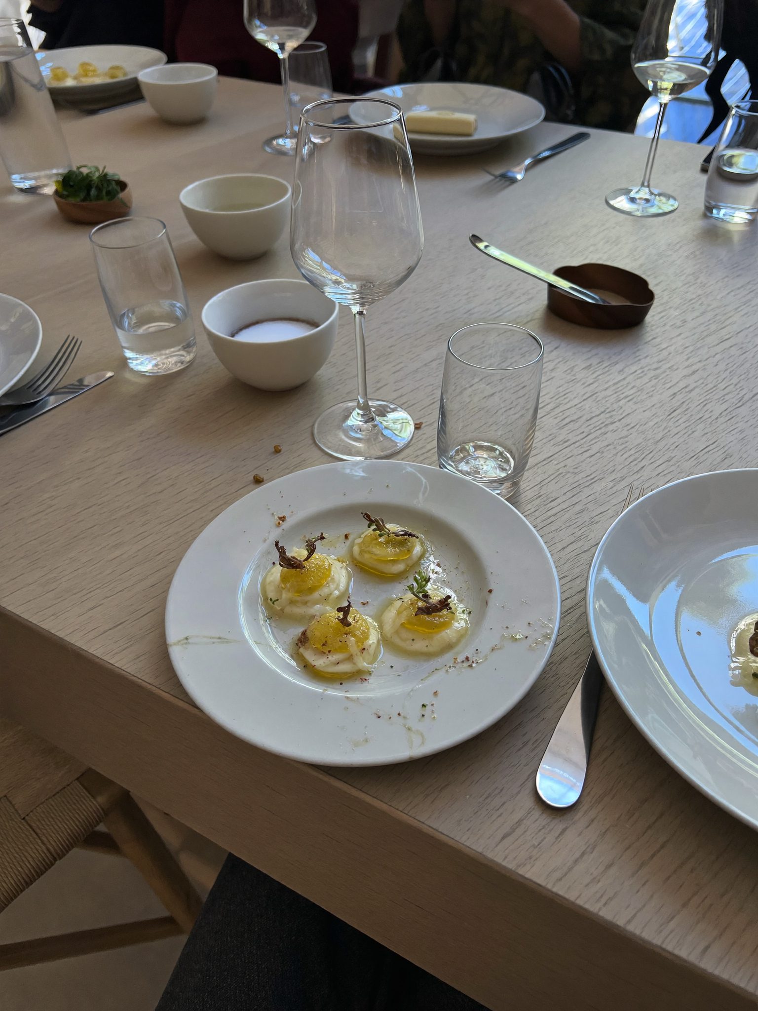 Mesa posta com copos de vinho sobre toalha de linho branca